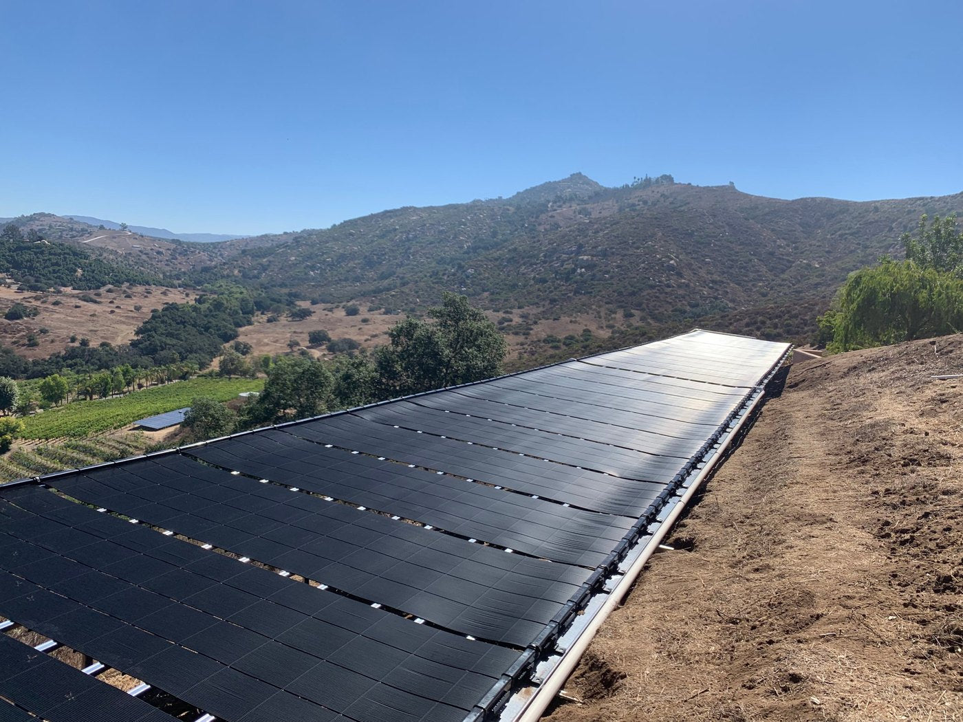 A solar heating panel array on a ground rack above a valley