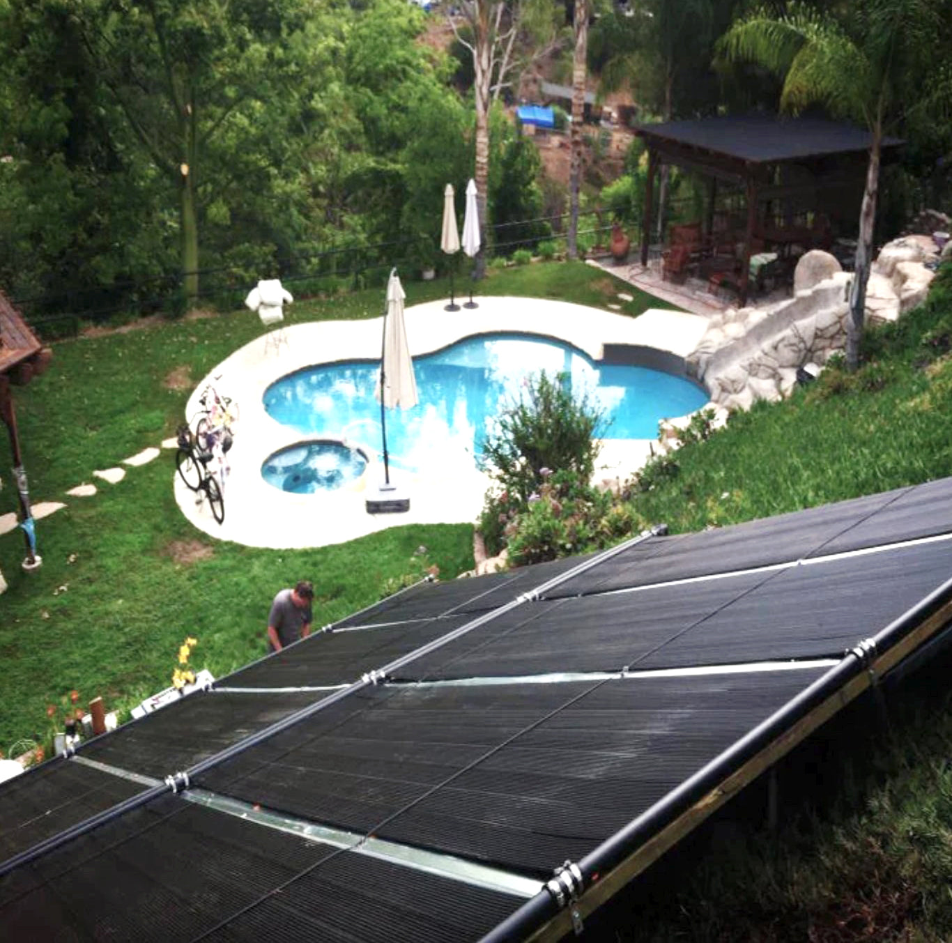 SwimEasy solar pool heating panels installed on a rack overlooking a backyard swimming pool